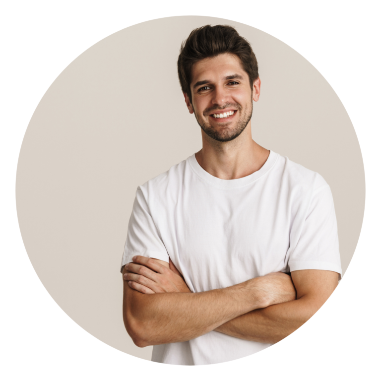 Portrait d’un homme souriant, bras croisés, t-shirt blanc, fond neutre.