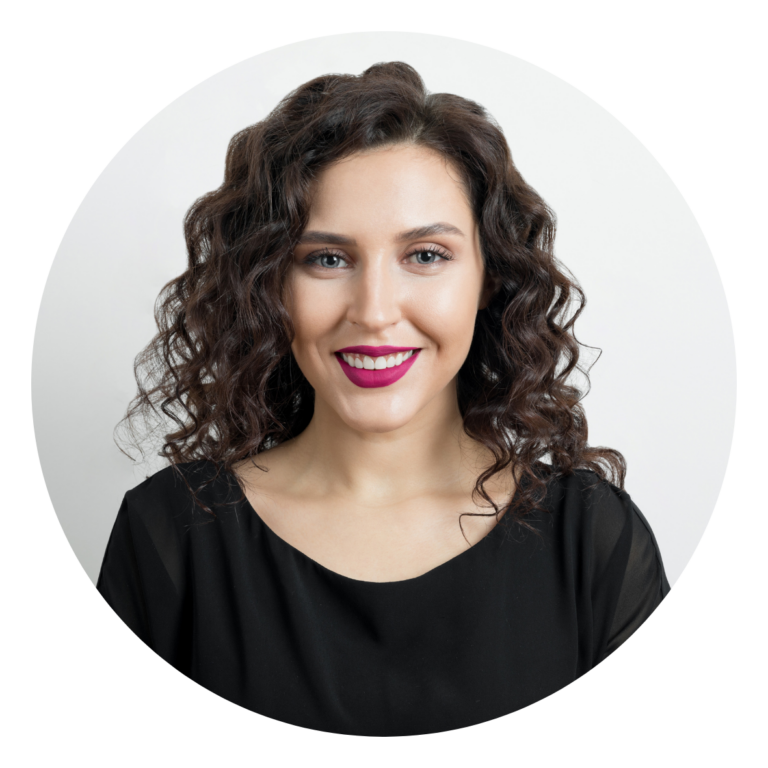 Portrait d’une femme aux cheveux bouclés, sourire, rouge à lèvres rose, haut noir, fond clair.